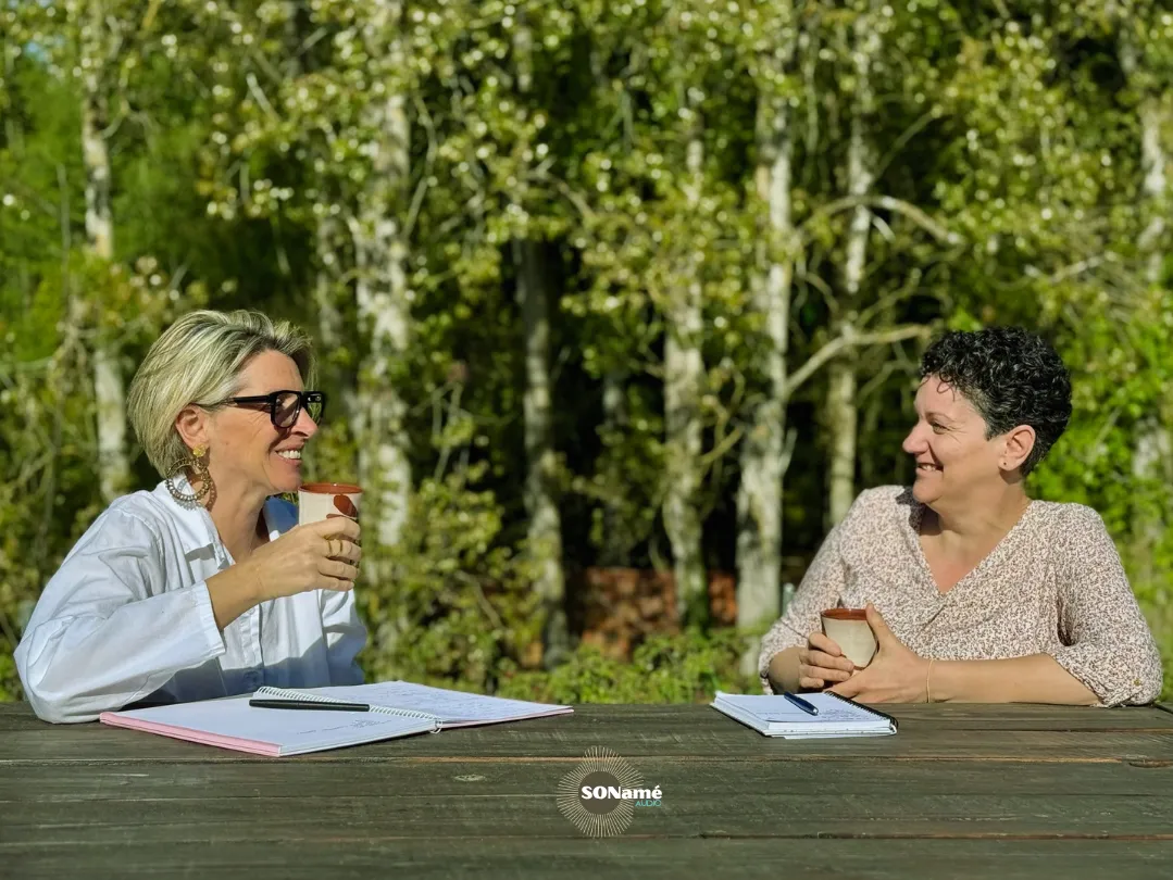 Marie-Laure et Sophie, les fondatrices, en discussion souriante autour d'une table en extérieur.