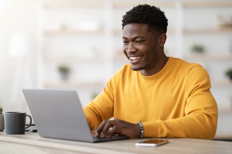 Un collaborateur souriant travaille sur son ordinateur portable, détendu.